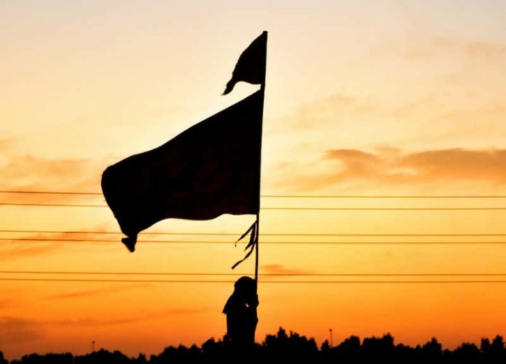silhouette of man holding flag during sunset